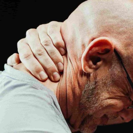 Man clutching his neck in pain.